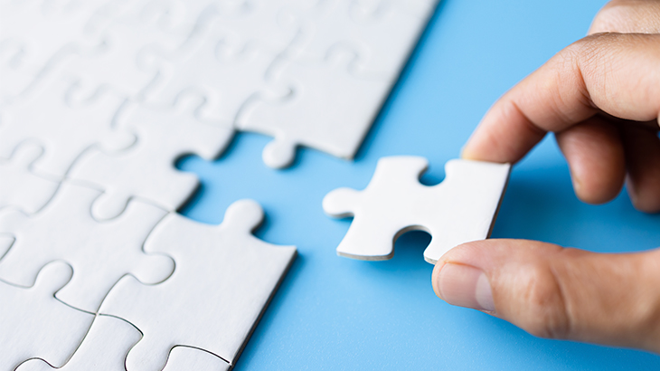 A hand putting the last piece of a jigsaw puzzle.